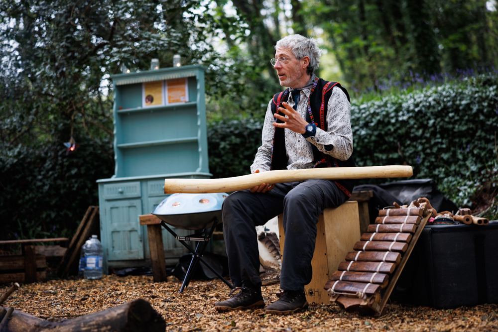 Storyteller sitting in a woodland with musical instruments